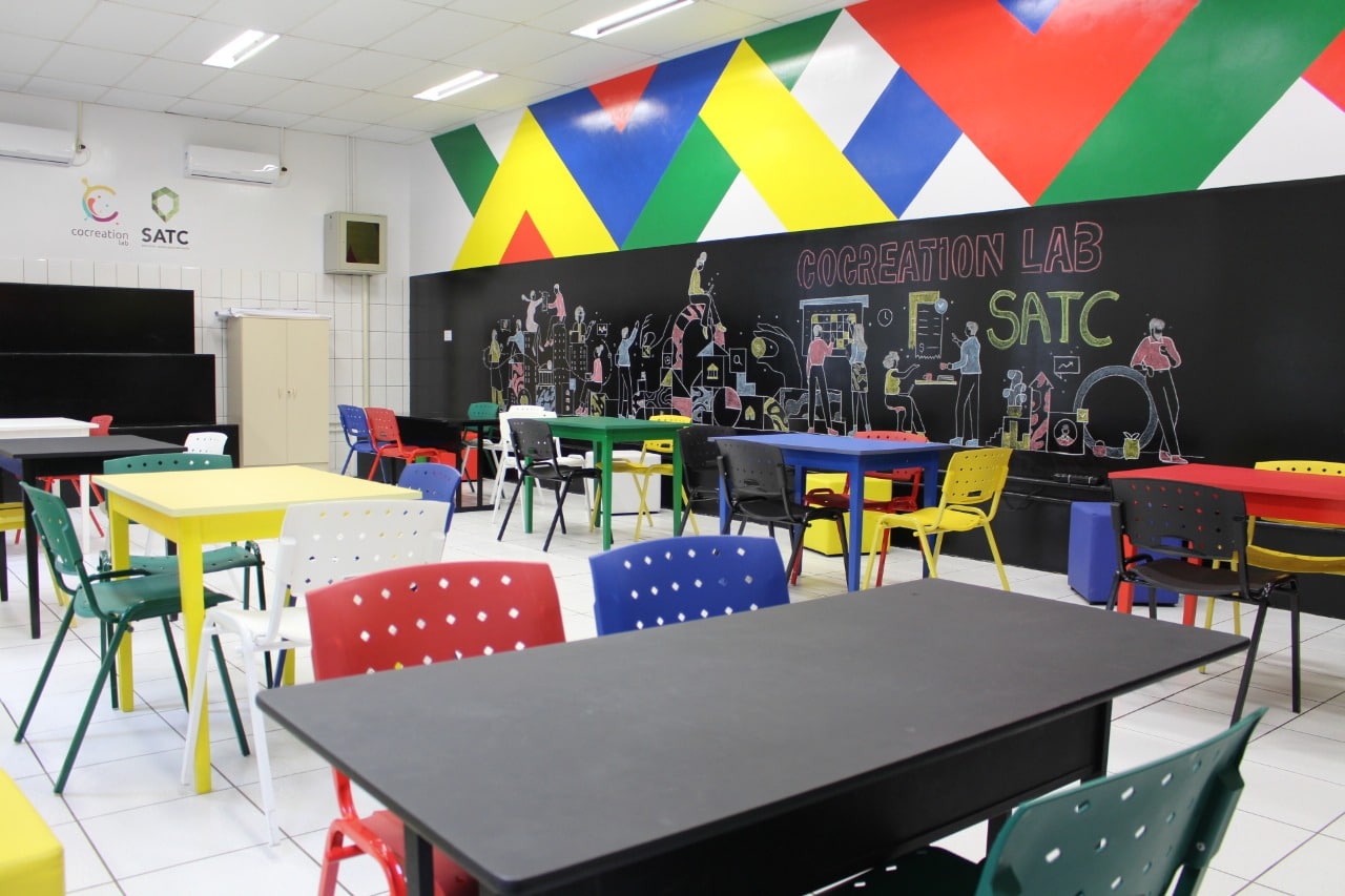 Laboratório do Cocreation Lab Satc é colorido com mesas e cadeiras para que as mentorias aconteçam.